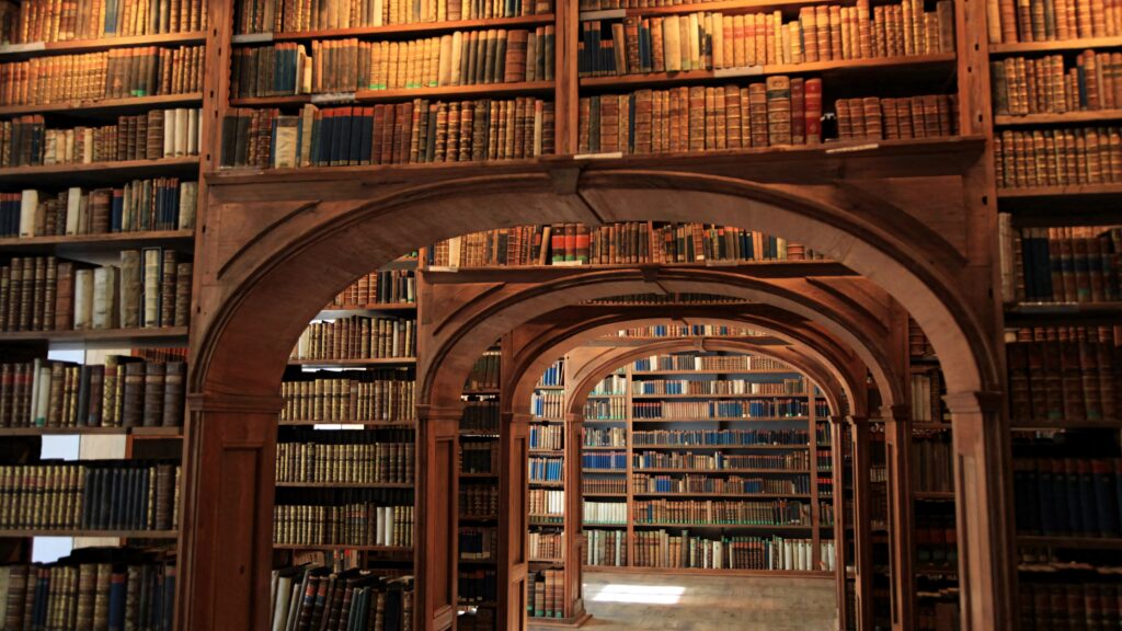 Dark academia library wallpaper with wooden archways and vintage leather-bound books background