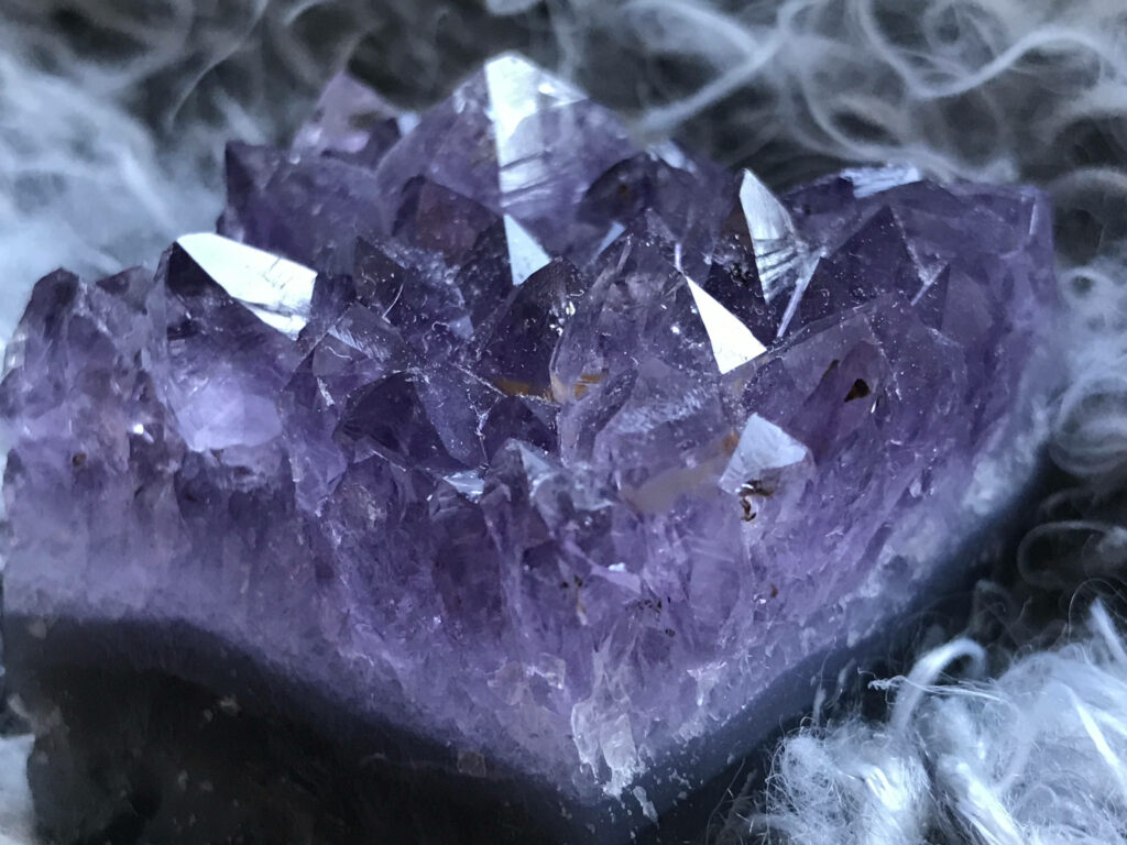 Close-up of dark amethyst shards with sharp crystals and deep purple hues on ethereal background Wallpaper