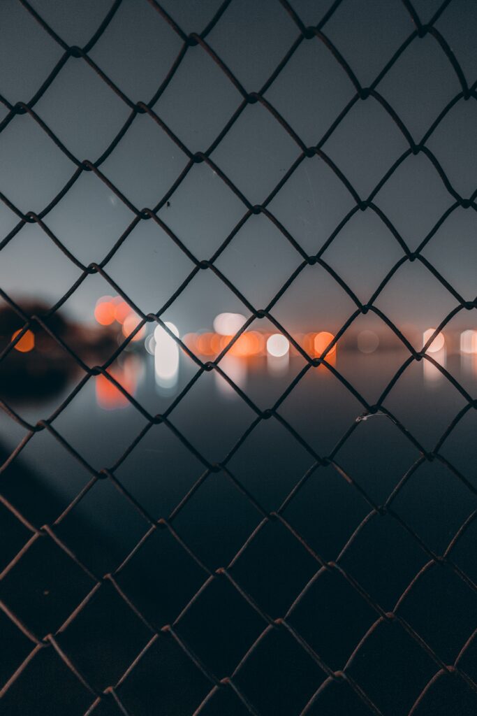 Dark Blurred Wallpaper: Metallic Mesh Fence & Glowing Bokeh Lights