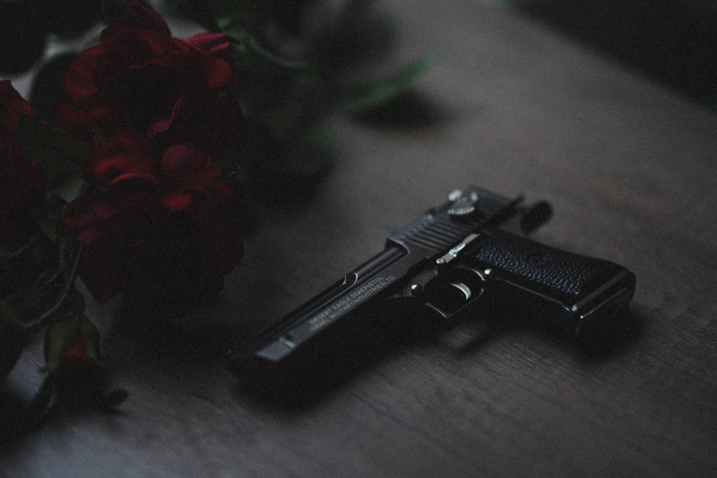 Black Desert Eagle 50AE pistol on wood with deep red roses cinematic dark wallpaper background