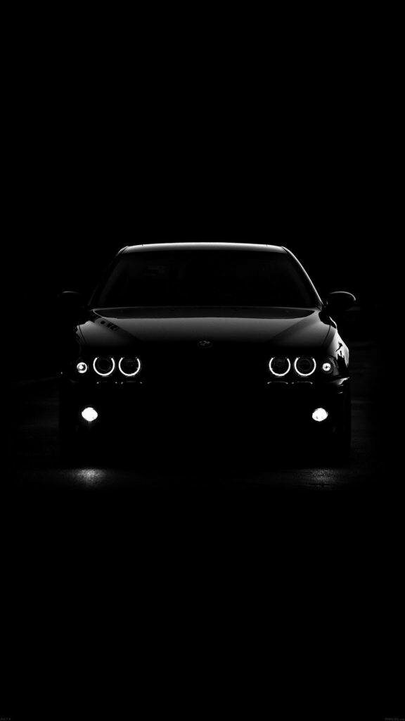 Dark Majesty: A Captivating Portrait of a Black BMW Embracing the Shadows, Enhanced by Luminous Headlights Wallpaper