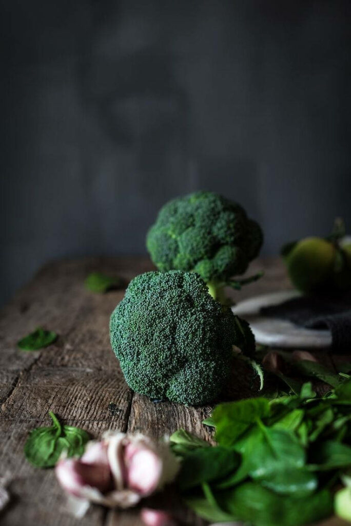 Fresh dark green broccoli florets with garlic on rustic wood background healthy food wallpaper
