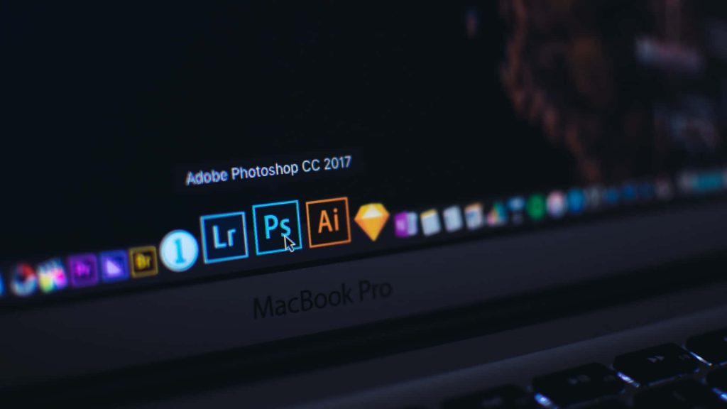 Dark-themed MacBook Pro screen with macOS dock highlighting Adobe Photoshop CC 2017 icon Wallpaper