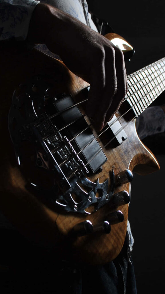 Rhythmic Tunes in the Shadows: Bass Guitar Background Melody Wallpaper
