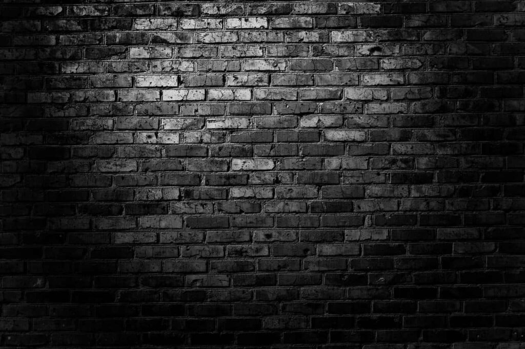Dramatic Black Brick Wall Wallpaper with Subtle Lighting Texture