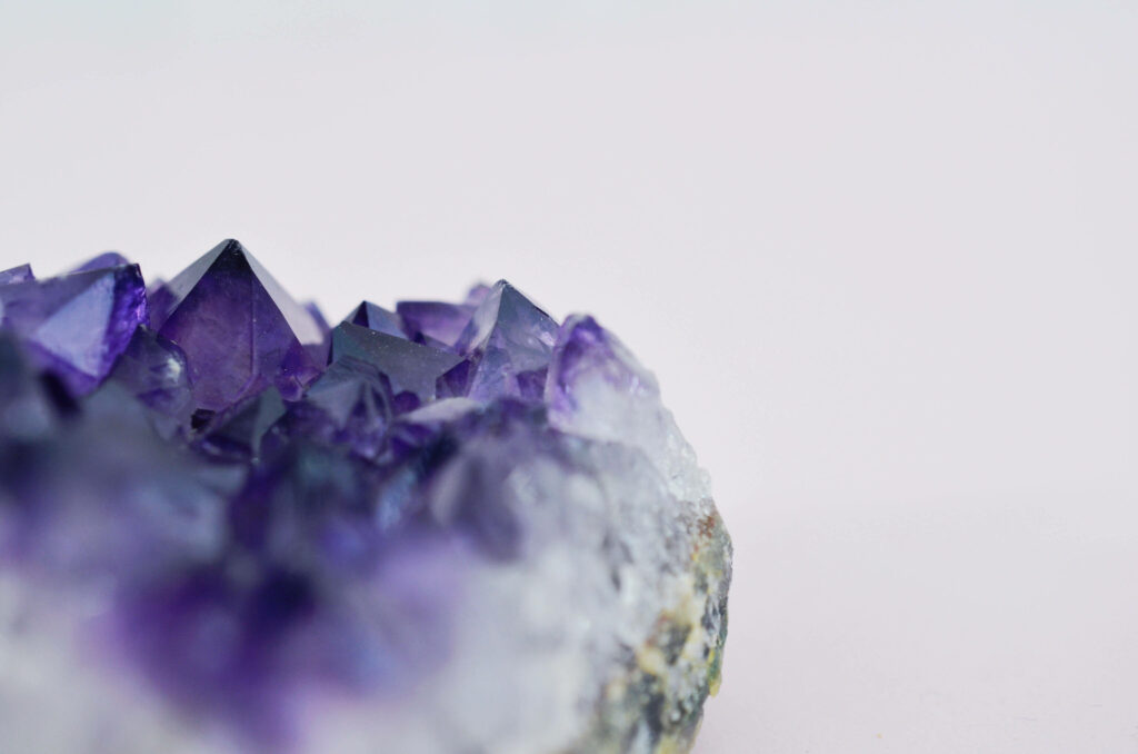 Close-up of dark violet amethyst geode with natural crystal formations on minimalist background Wallpaper