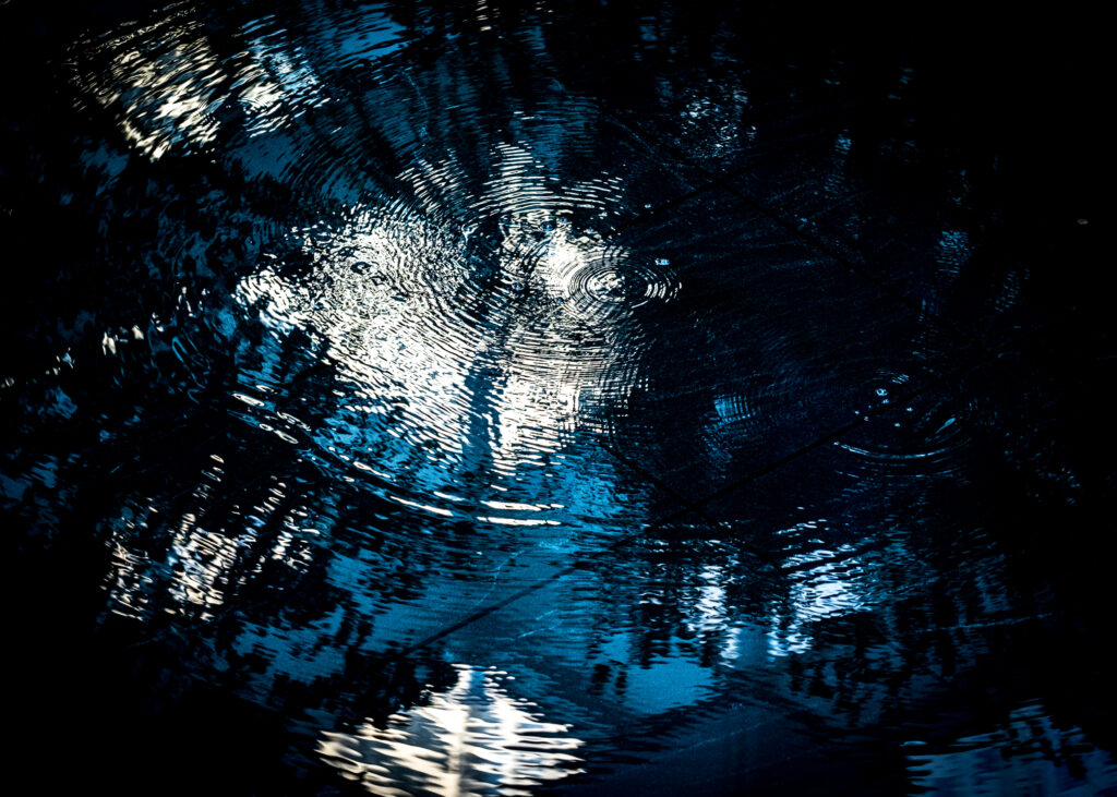 Dark water wallpaper with ripples and overlapping circles reflecting light and shadow patterns