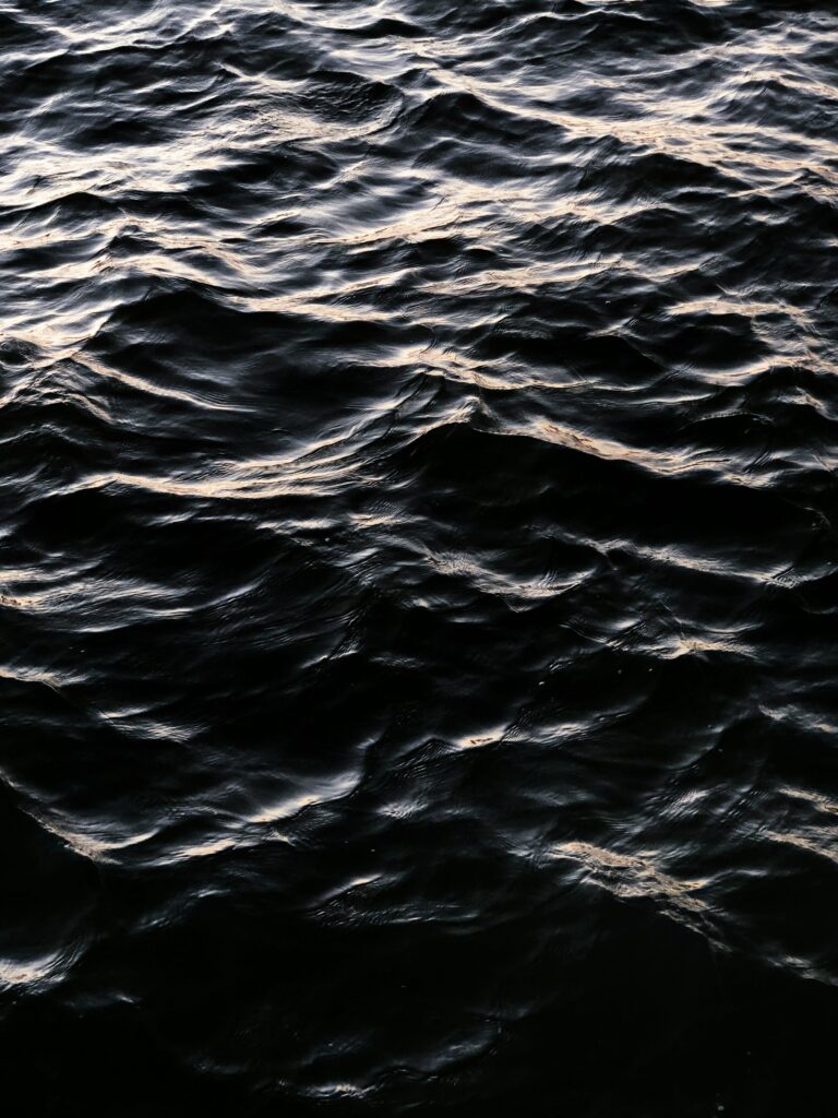 Dark wavy water wallpaper with gentle ripples and subtle glare creating serene atmosphere