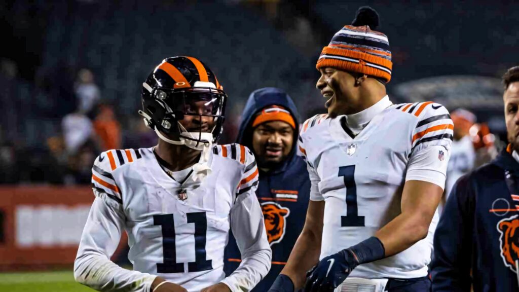 Darnell Mooney and Justin Fields in Chicago Bears uniforms sharing a moment during night game Wallpaper