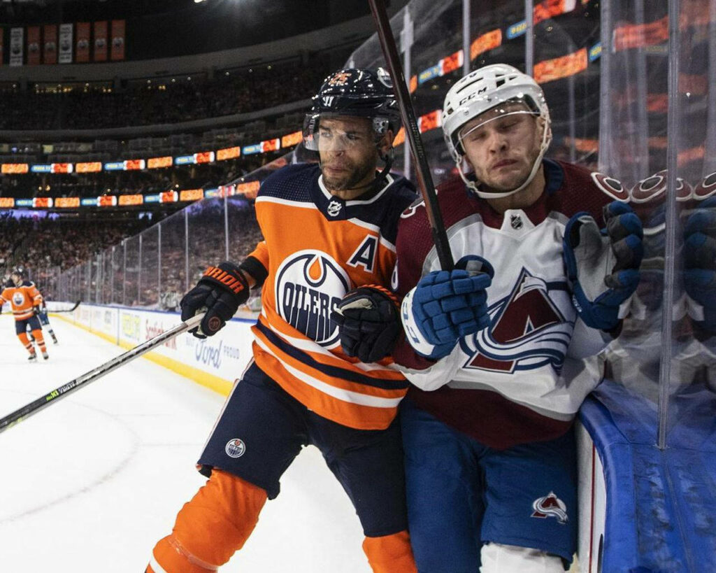 Darnell Nurse battles Mikko Rantanen along the glass in intense Edmonton Oilers vs Avalanche NHL game Wallpaper