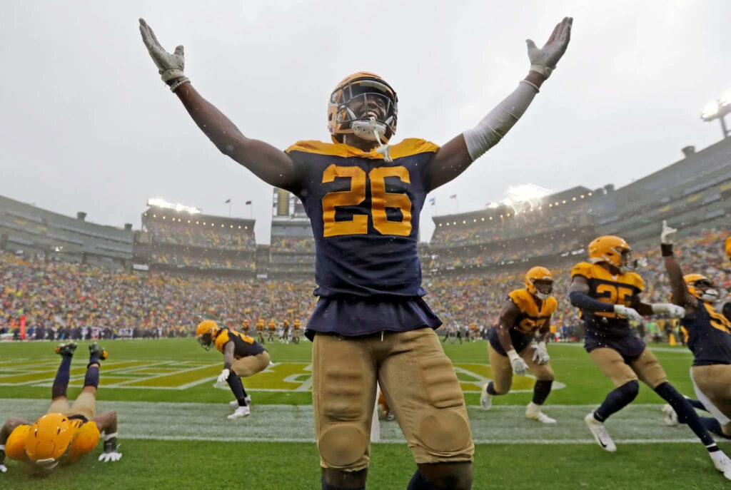 Darnell Savage Jr celebrating football touchdown in number 26 jersey with teammates in rain Wallpaper