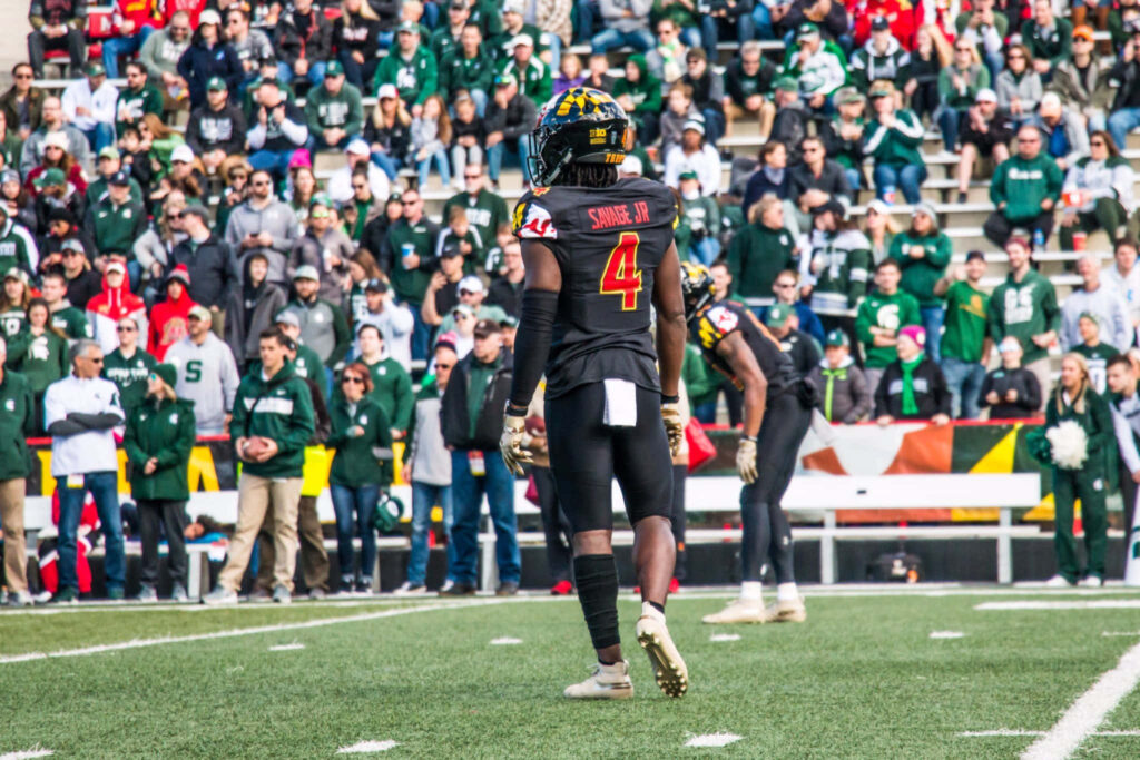 Darnell Savage Jr on football field in black and red uniform with vibrant stadium crowd background Wallpaper