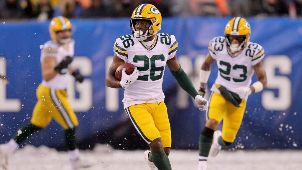 Darnell Savage Jr Green Bay Packers sprinting on snowy field in white yellow uniform with football Wallpaper