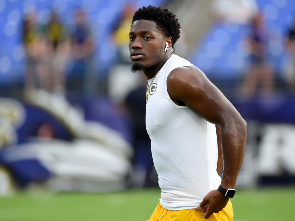 Darnell Savage Jr in white top and yellow shorts warming up on field with green gold stadium background Wallpaper