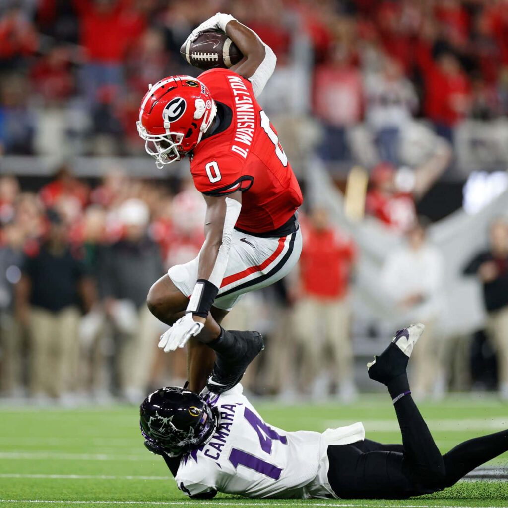 Darnell Washington airborne catch dynamic football game vibrant red black team colors stadium Wallpaper