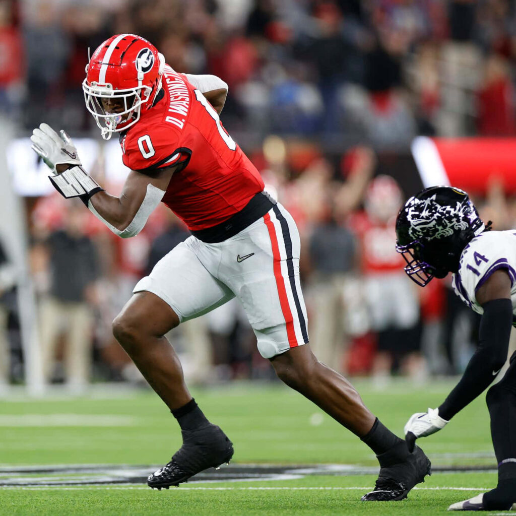 Darnell Washington football action evading tackle vibrant red white uniform stadium background Wallpaper