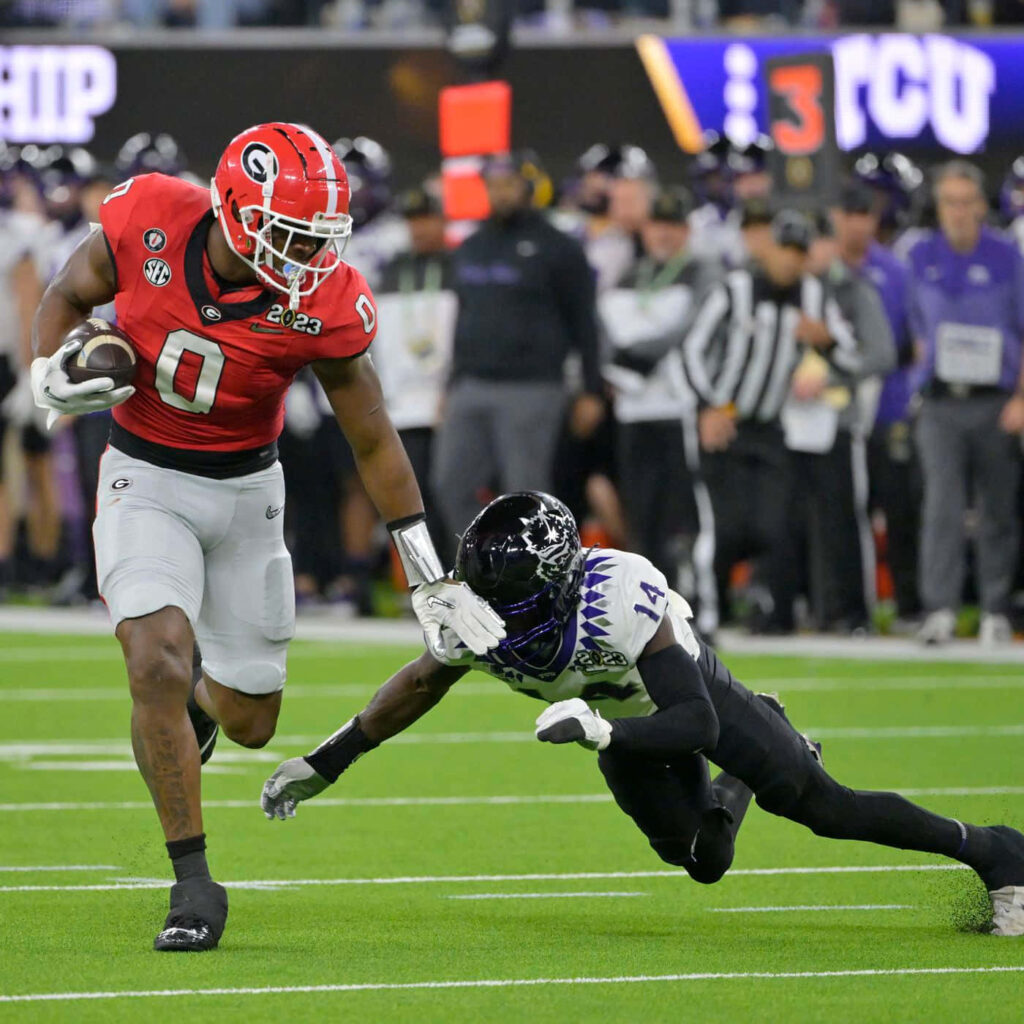 Darnell Washington powering forward in Georgia football uniform evading TCU defender wallpaper