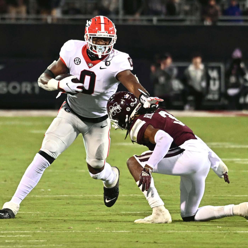 Darnell Washington powering through defender in red white Georgia uniform during college football game Wallpaper