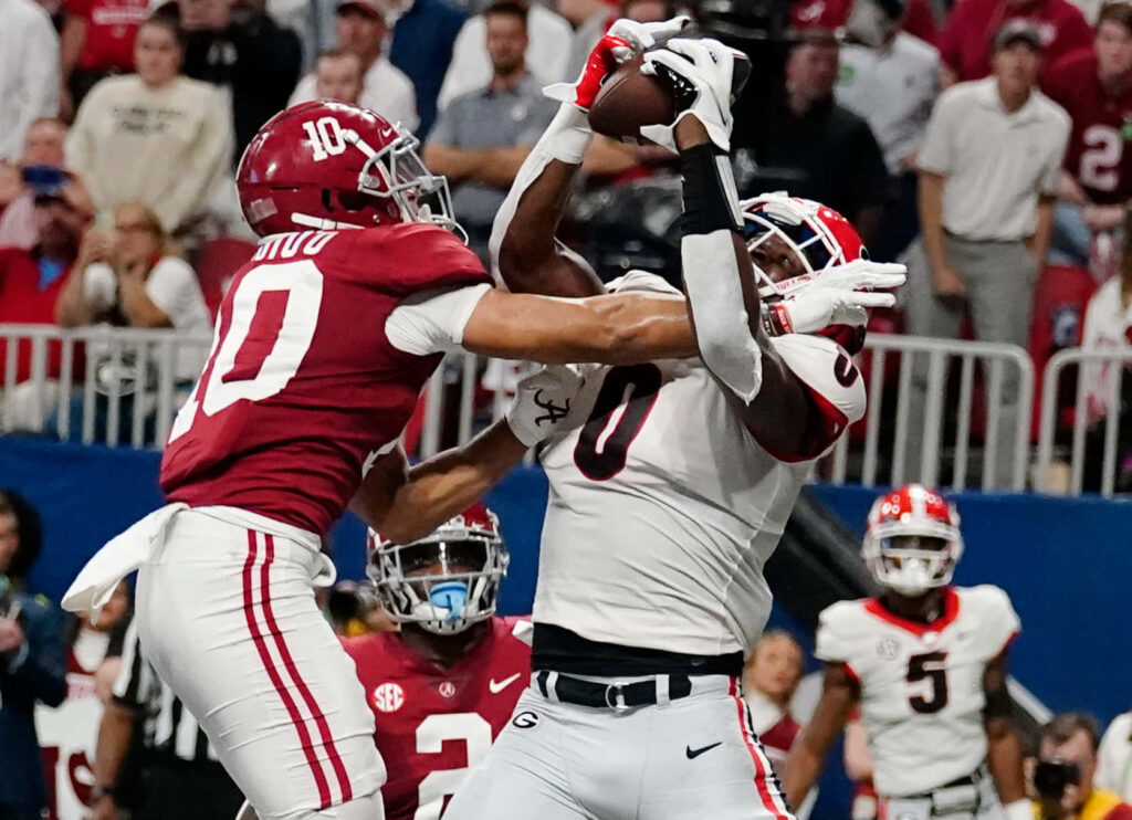 Darnell Washington battles defender in college football game showcasing athleticism and intensity Wallpaper
