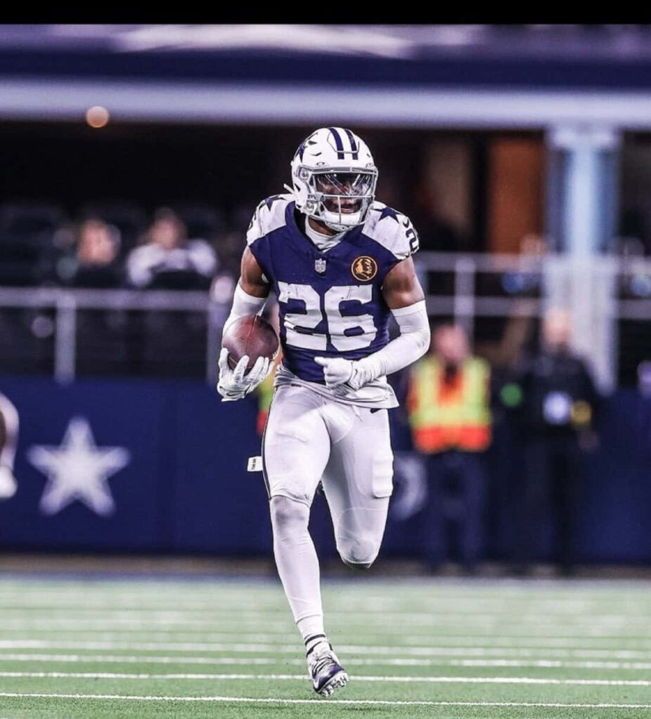Daron Bland running on football field in Dallas Cowboys gear with stadium energy background Wallpaper
