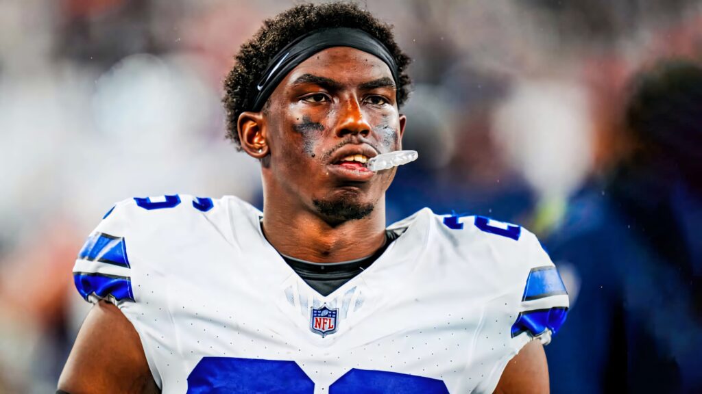 Daron Bland in white Dallas Cowboys jersey focused on football field with blurred stadium background Wallpaper