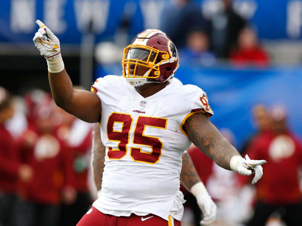 Daron Payne celebrating in burgundy and gold Washington uniform on vibrant stadium background Wallpaper