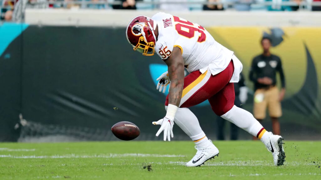 Daron Payne number 95 in Washington uniform aggressively recovers loose ball on green football field Wallpaper