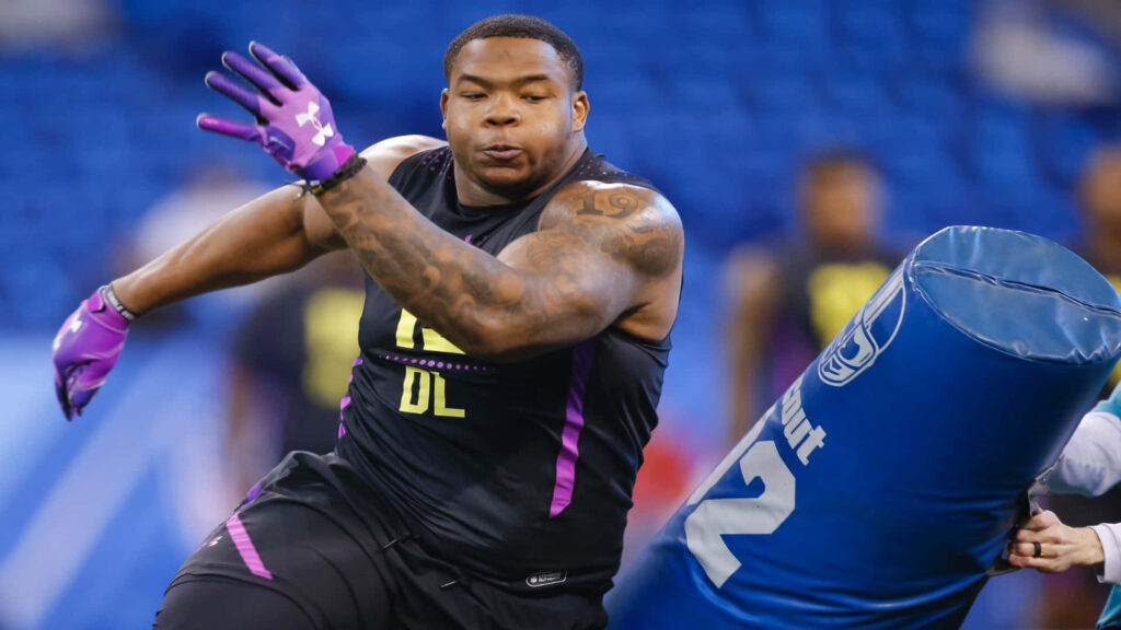 Daron Payne football combine drill intense focus black uniform purple gloves tackling dummy Wallpaper