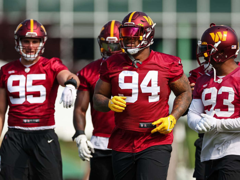 Daron Payne number 94 in Washington Commanders red jersey and yellow helmet during football practice Wallpaper