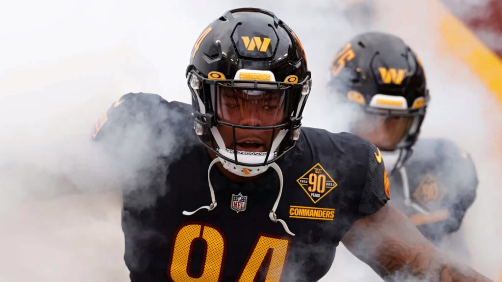 Daron Payne Washington Commanders in black gold uniform emerges from smoke intense football wallpaper