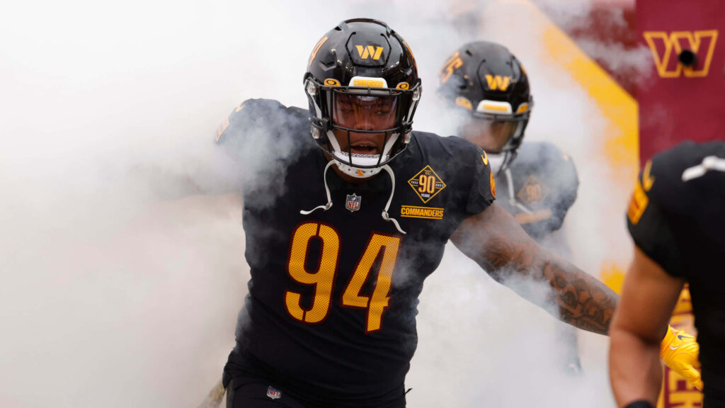 Daron Payne in Washington Commanders uniform charges through smoke onto football field intense action Wallpaper