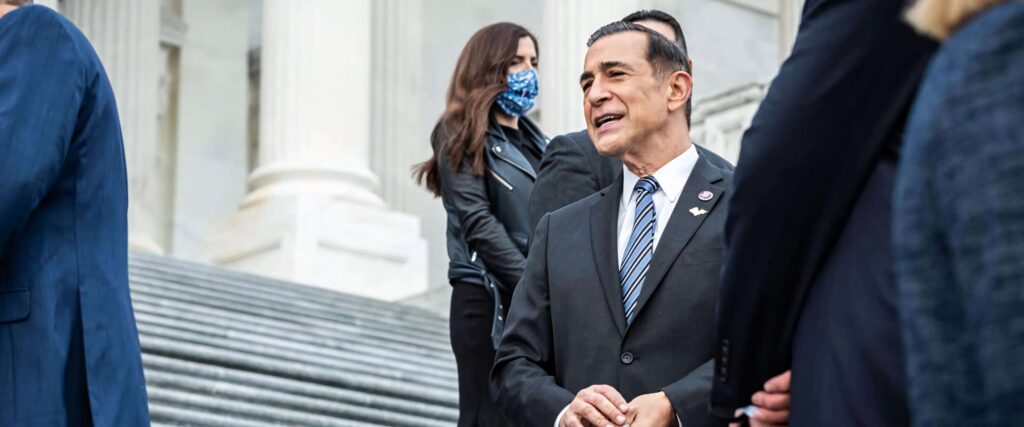 Darrell Issa in sharp suit standing confidently on US Capitol steps with architectural columns background Wallpaper