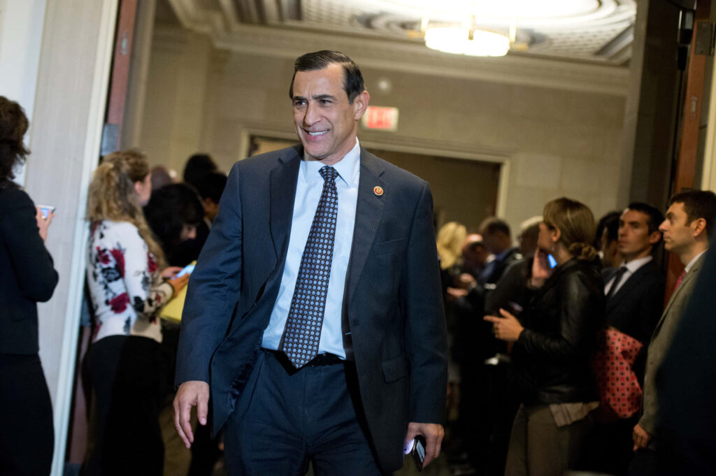 Darrell Issa in dark suit confident in busy hallway warm lighting professional setting wallpaper