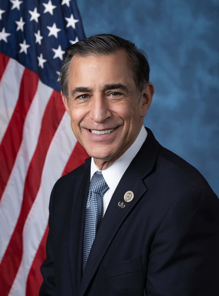 Darrell Issa formal portrait dark suit patterned tie blue backdrop American flag patriotic Wallpaper