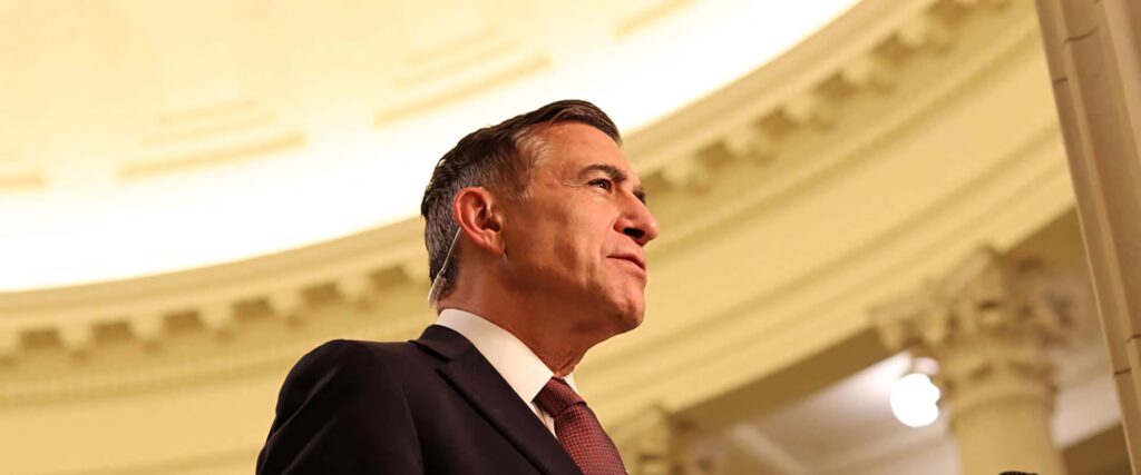 Low-angle photo of Darrell Issa in formal attire with grand dome background and warm lighting Wallpaper