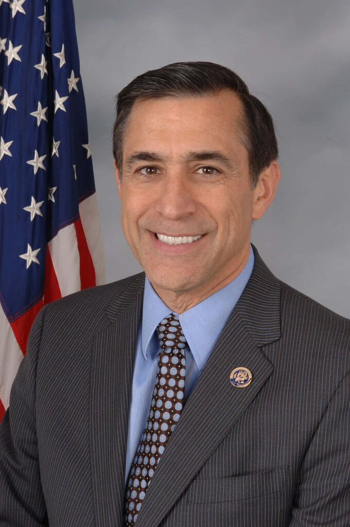 Professional portrait of Darrell Issa in suit and tie with American flag background leadership theme Wallpaper