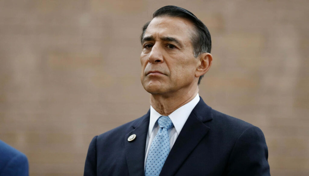 Darrell Issa serious expression dark suit light blue tie formal portrait neutral background wallpaper