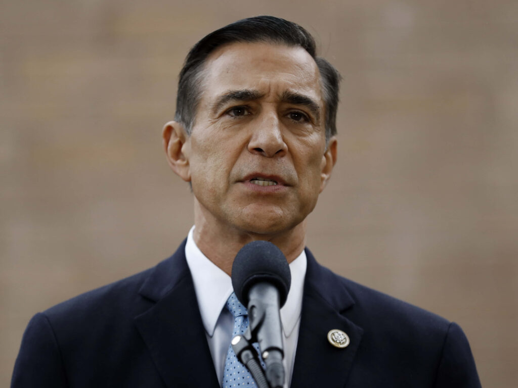 Darrell Issa speaking into microphone wearing dark suit and light blue tie with serious expression Wallpaper