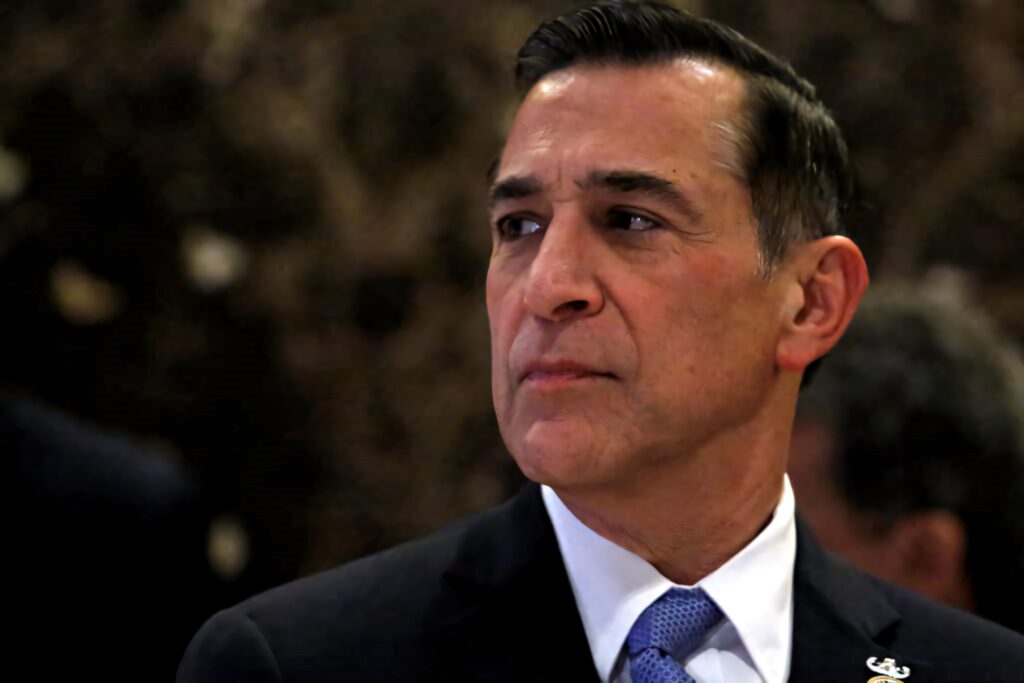 Darrell Issa in suit and tie thoughtful portrait warm lighting dark blurred background professional Wallpaper