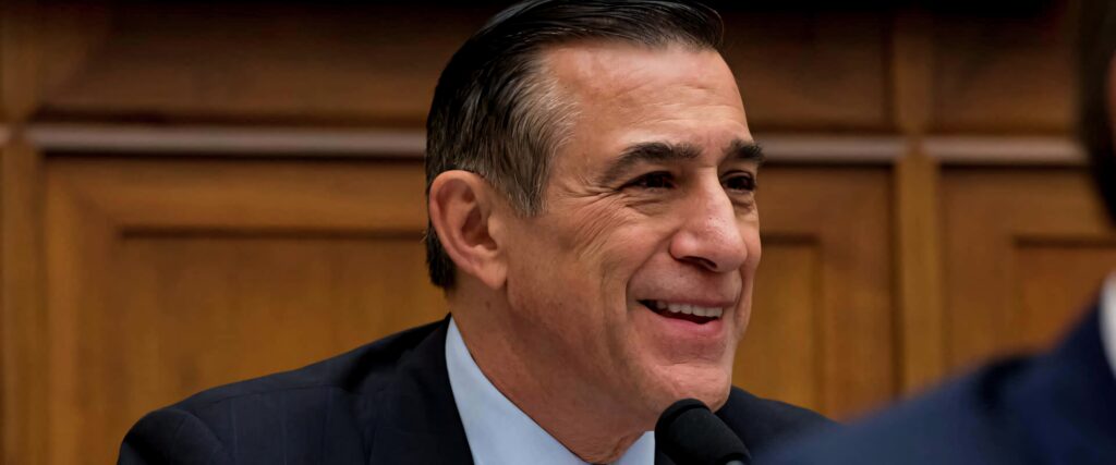 Darrell Issa smiling in dark suit against rich wooden wall professional warm tone portrait Wallpaper