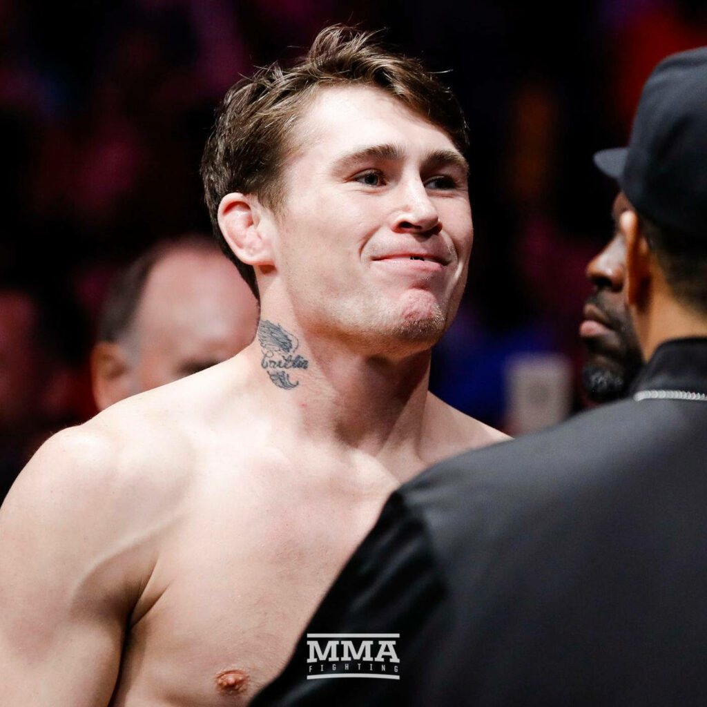 Darren Till shirtless confident before MMA fight with colorful arena lights and energetic crowd Wallpaper