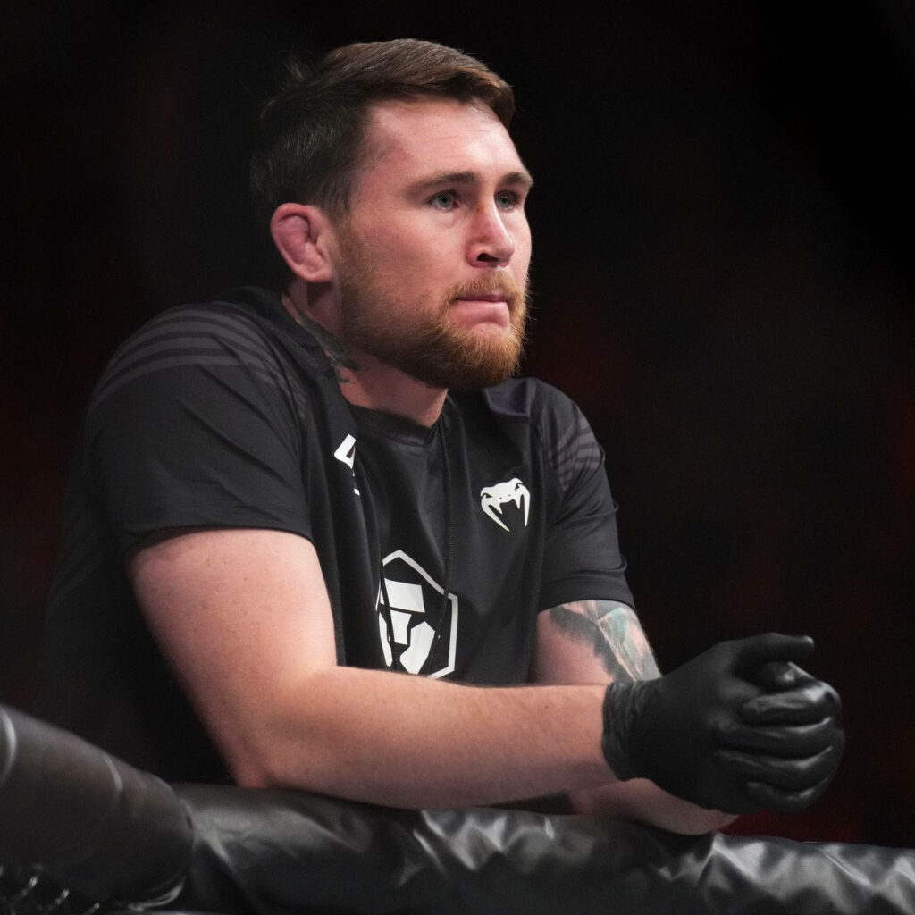 Darren Till focused MMA fighter leaning on ring with gloves black shirt dark background wallpaper