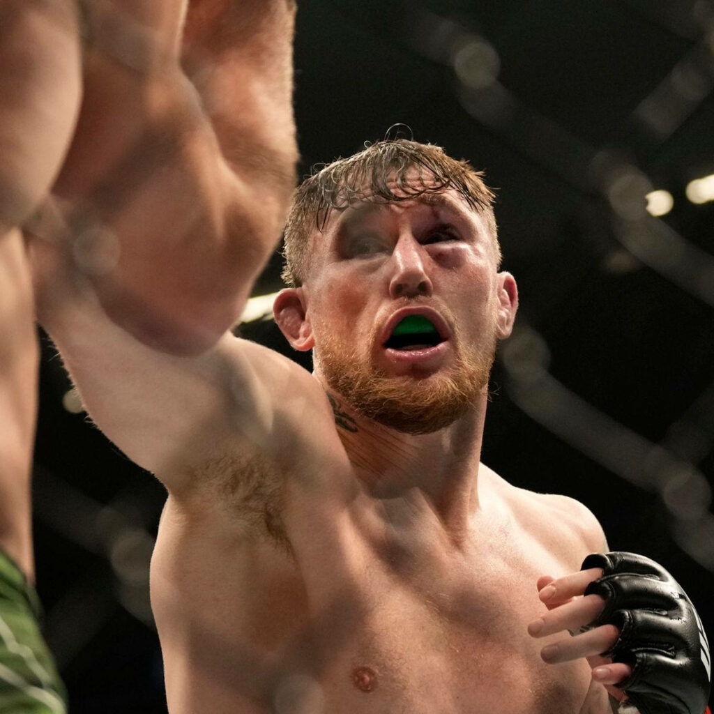 Darren Till mid-punch intense MMA action sweat focus athleticism in cage arena wallpaper background