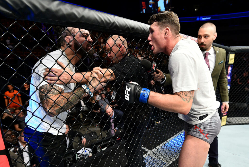 Darren Till taunting opponent UFC octagon intense expressions dynamic MMA fight arena lights Wallpaper