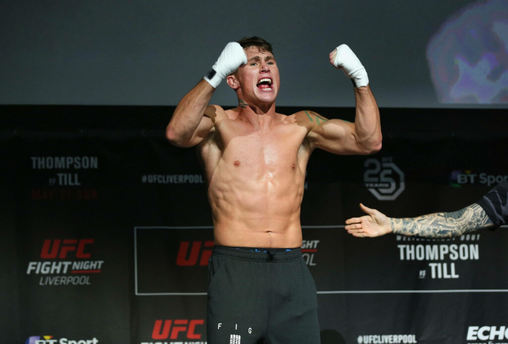 Darren Till shirtless flexing muscles with wrapped gloves at UFC fight night weigh-in arena Wallpaper