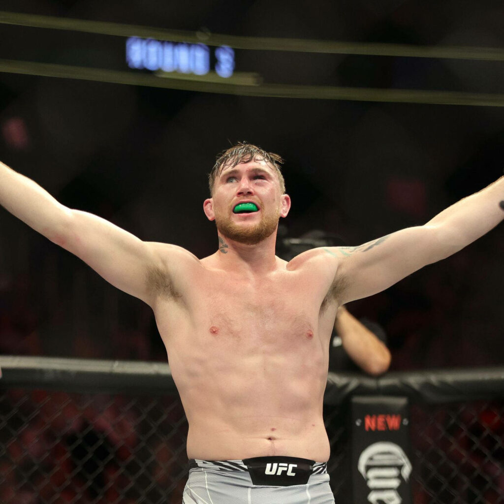 Darren Till celebrating MMA victory with raised arms vibrant lighting and intense focus wallpaper