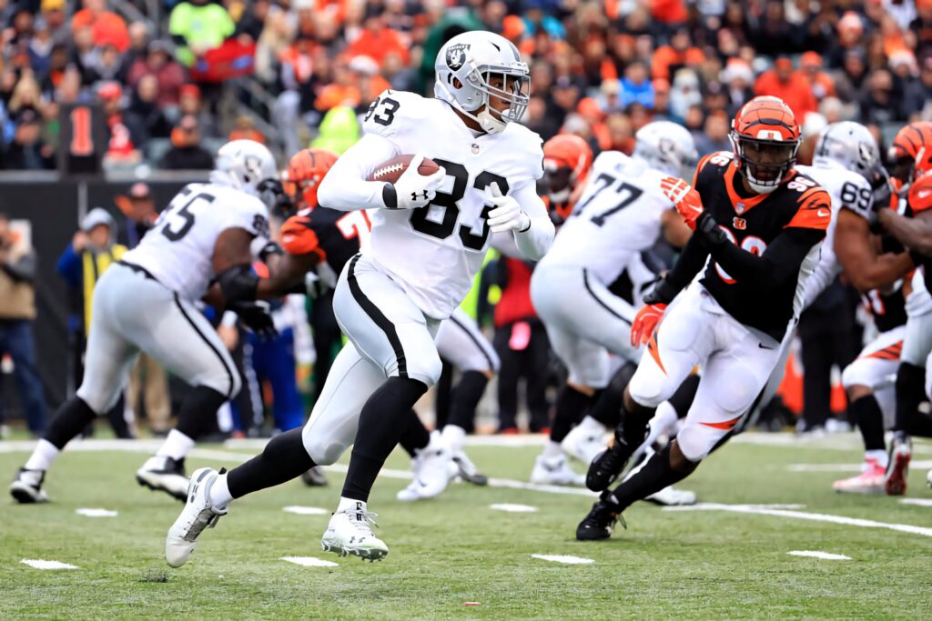 Darren Waller in Raiders uniform runs with football as defenders close in vibrant NFL action Wallpaper