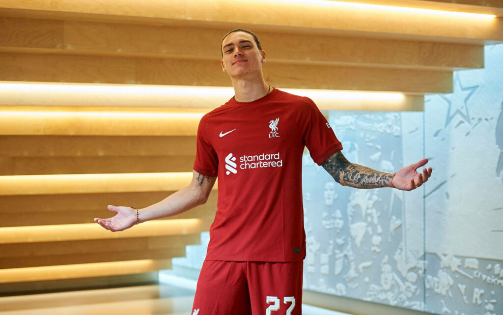 Darwin Núñez in Liverpool FC kit posing confidently with warm artistic background and red colors Wallpaper
