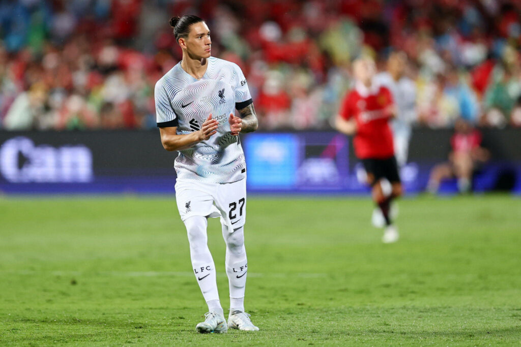 Darwin Núñez clapping on field wearing white Liverpool FC kit vibrant stadium crowd background wallpaper