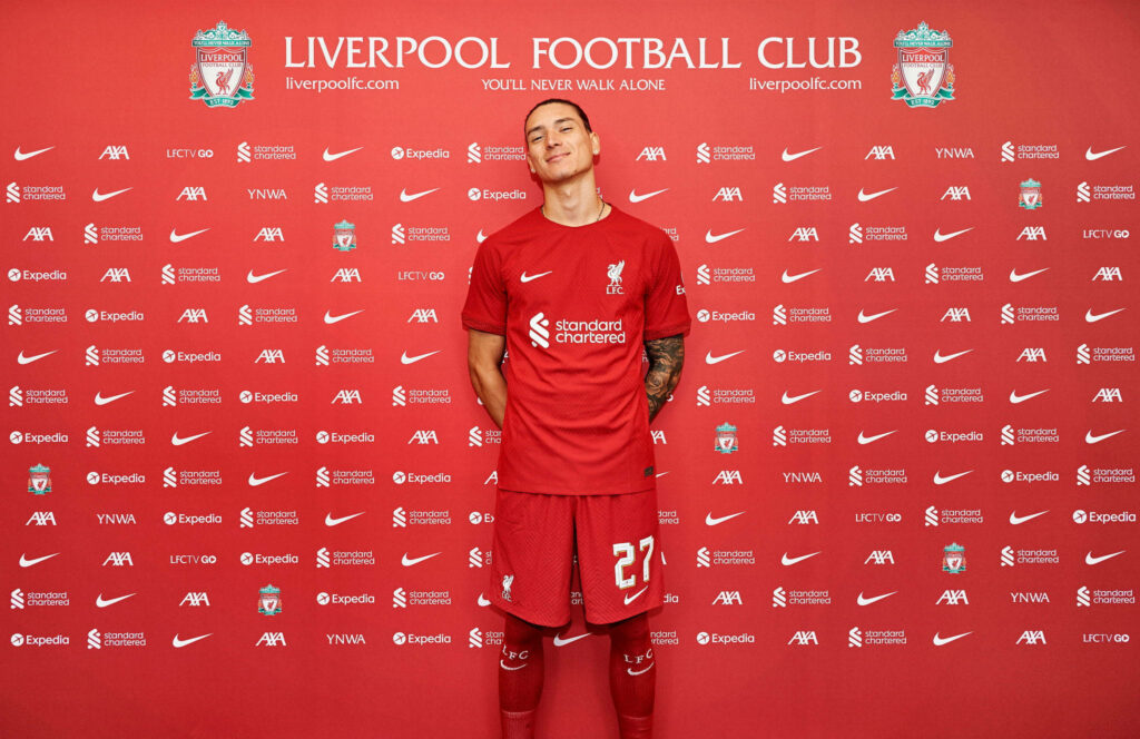 Darwin Núñez in Liverpool kit with club crest and sponsor logos on vibrant red background wallpaper